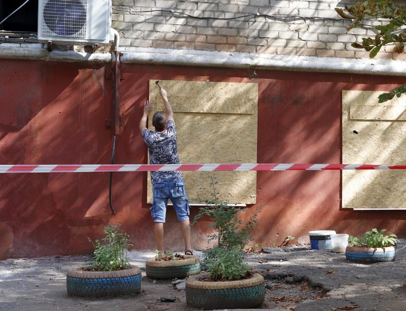 Worker boarding up a broken window after a break-in