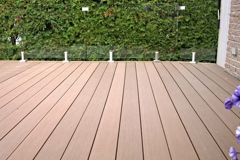 Modern glass panel railing on a finished deck