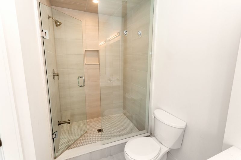 Frameless glass walk-in shower door installed in a tiled bathroom
